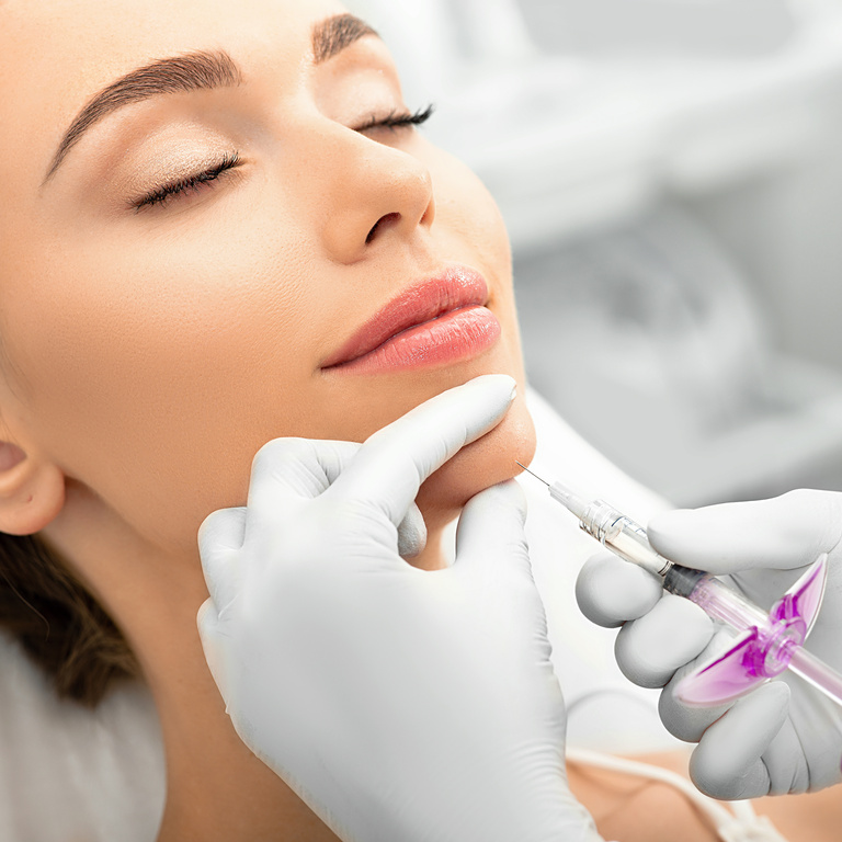 Woman during skin tightening procedure, injection of dermal filler into a female face. The anti-aging procedure, facial rejuvenation